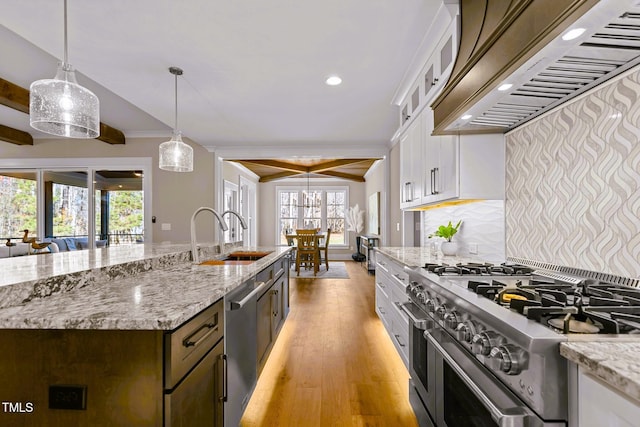 kitchen with custom exhaust hood, white cabinets, hanging light fixtures, sink, and appliances with stainless steel finishes