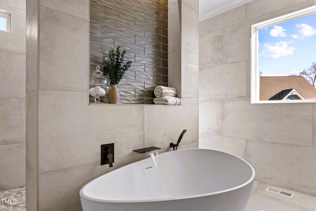 bathroom with a bathing tub and tile walls