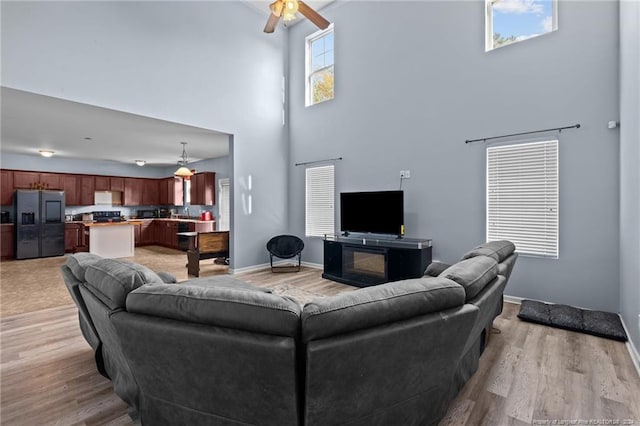 living room with a high ceiling, light hardwood / wood-style floors, and ceiling fan