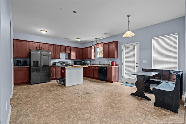 kitchen featuring stainless steel fridge, a kitchen breakfast bar, black dishwasher, a kitchen island, and hanging light fixtures