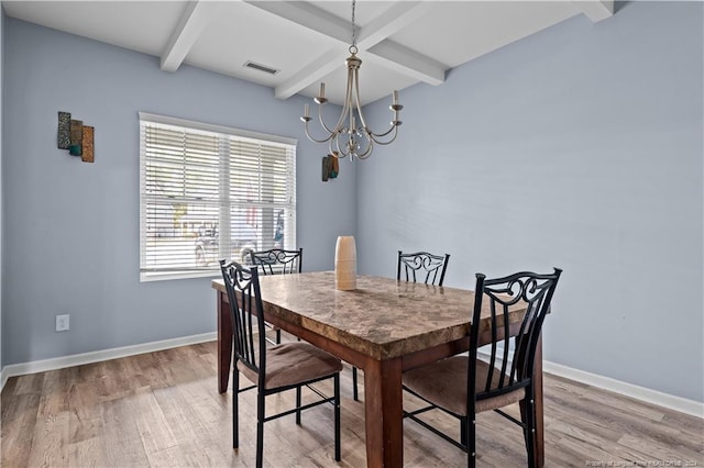 dining area featuring wood-type flooring, an inviting chandelier, and beam ceiling