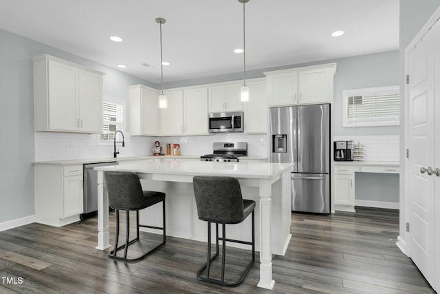 kitchen with pendant lighting, a center island, white cabinets, dark hardwood / wood-style floors, and appliances with stainless steel finishes