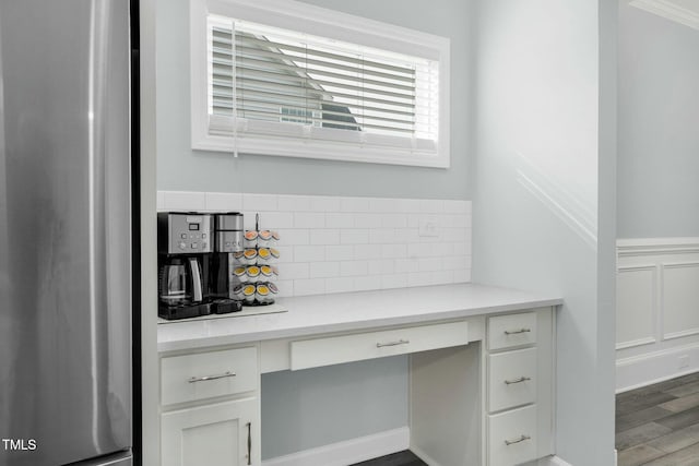 unfurnished office featuring hardwood / wood-style flooring, built in desk, and ornamental molding