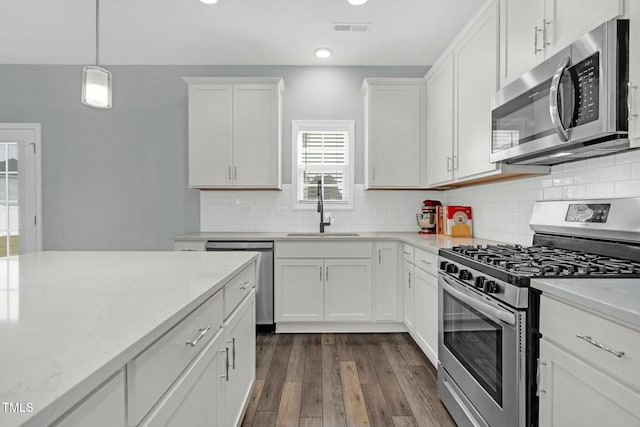 kitchen with white cabinetry, sink, dark hardwood / wood-style flooring, decorative backsplash, and appliances with stainless steel finishes