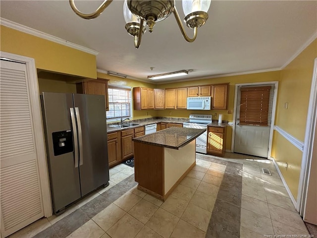 kitchen with a sink, white appliances, a kitchen island, and crown molding