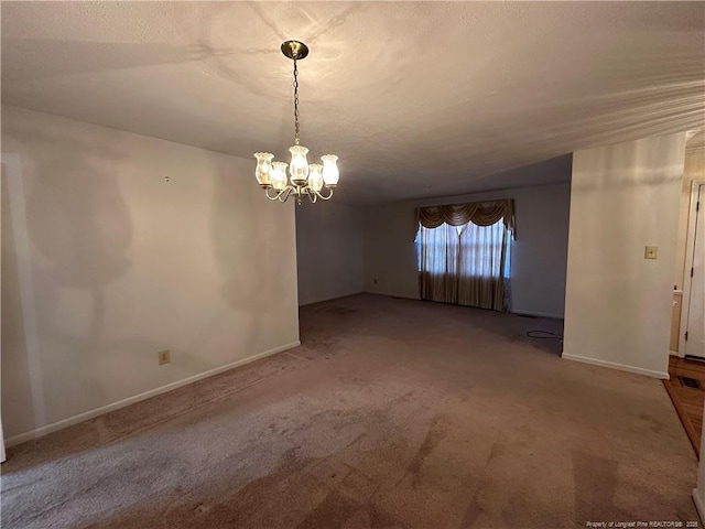 unfurnished dining area featuring carpet, a textured ceiling, a chandelier, and baseboards