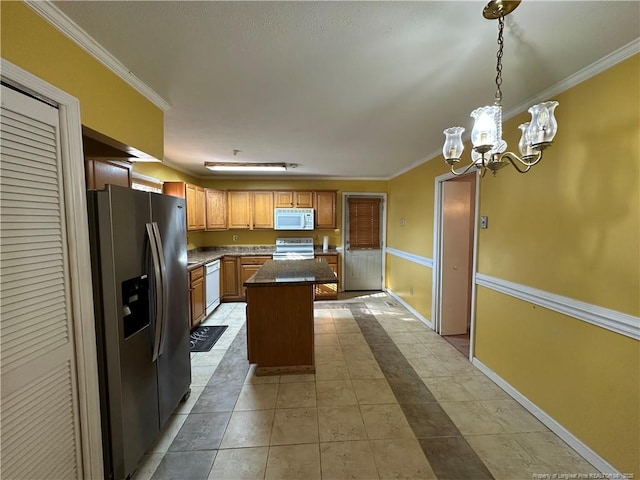 kitchen with a center island, dark countertops, ornamental molding, white appliances, and baseboards