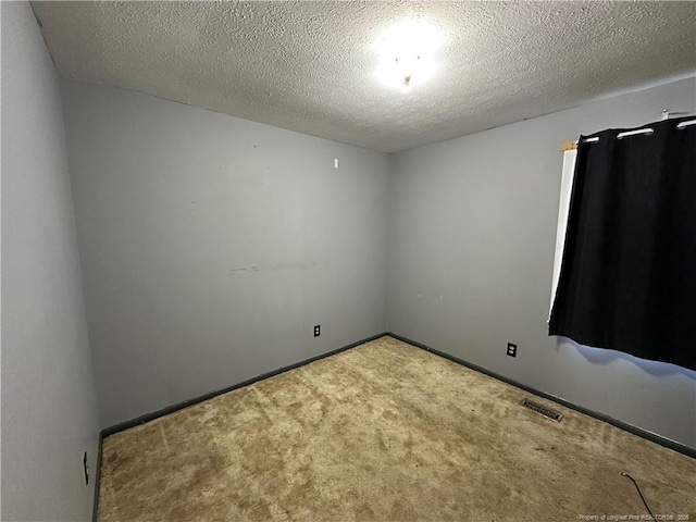 carpeted empty room featuring baseboards, visible vents, and a textured ceiling