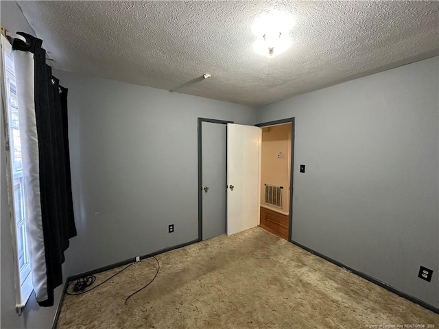 unfurnished bedroom featuring a closet, visible vents, a textured ceiling, and carpet flooring