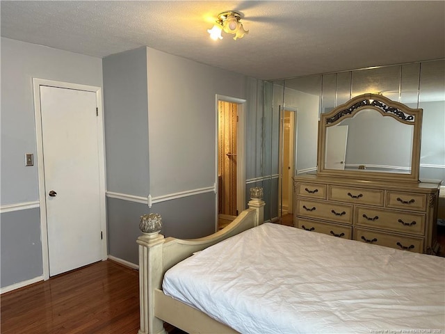 bedroom with a textured ceiling and wood finished floors