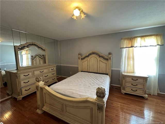 bedroom with a textured ceiling and dark wood-style flooring