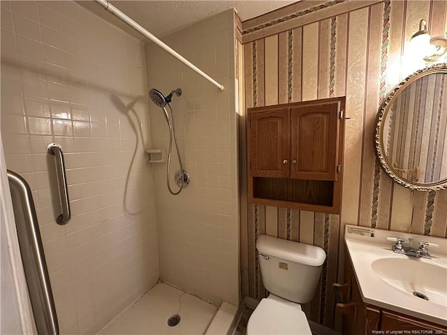 bathroom with toilet, a shower stall, a textured ceiling, and vanity