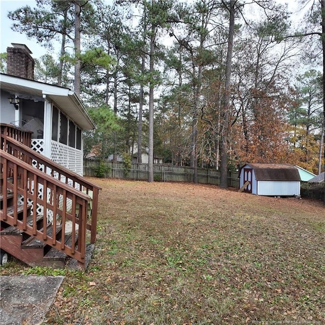 view of yard featuring a sunroom, a fenced backyard, a storage unit, and an outdoor structure