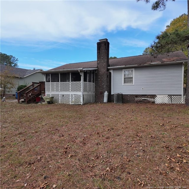 rear view of property featuring a sunroom, central AC, a yard, and a chimney