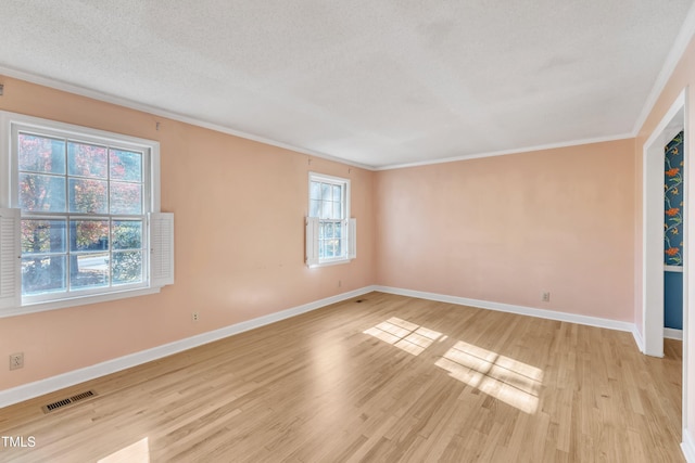 spare room featuring a textured ceiling, light hardwood / wood-style flooring, and crown molding