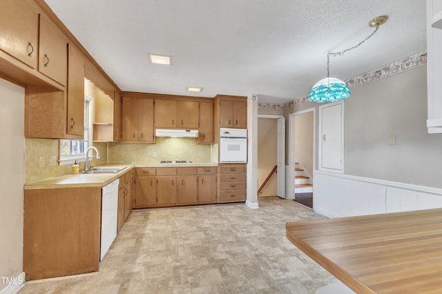 kitchen with a textured ceiling, white appliances, decorative light fixtures, and sink