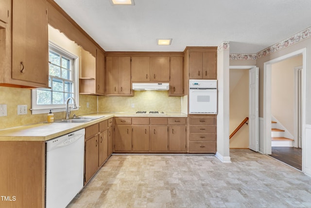 kitchen featuring decorative backsplash, white appliances, and sink