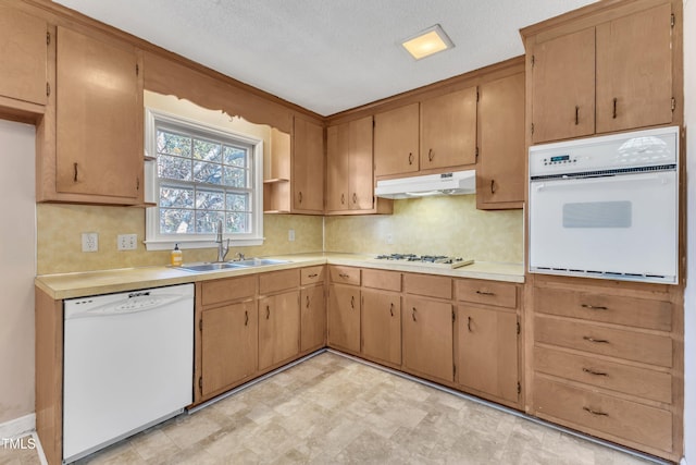 kitchen with a textured ceiling, backsplash, white appliances, and sink