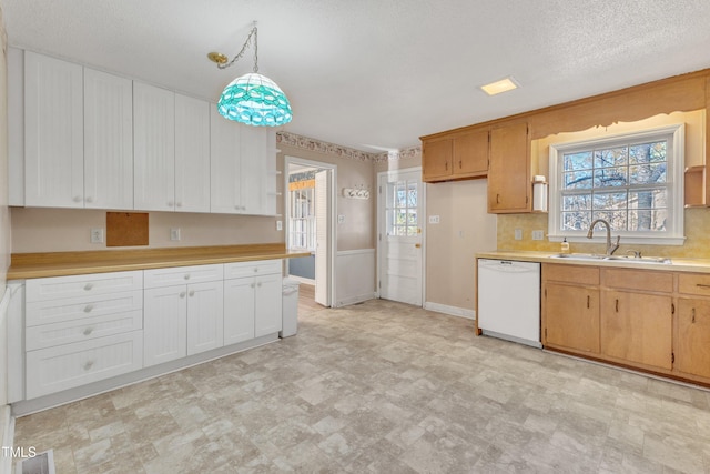 kitchen featuring decorative light fixtures, plenty of natural light, white dishwasher, and sink