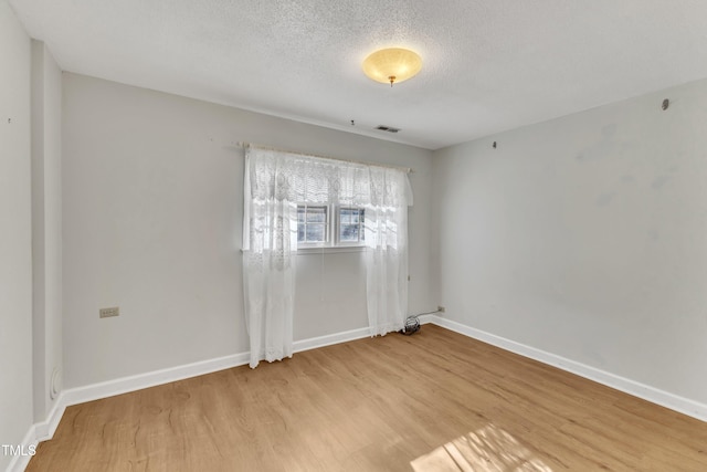 empty room featuring light hardwood / wood-style flooring and a textured ceiling