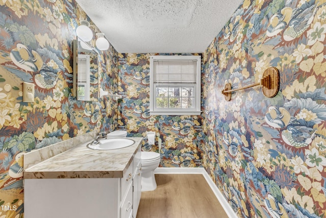 bathroom featuring a textured ceiling, vanity, hardwood / wood-style flooring, and toilet