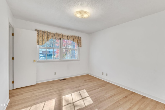 empty room featuring a textured ceiling and light hardwood / wood-style flooring