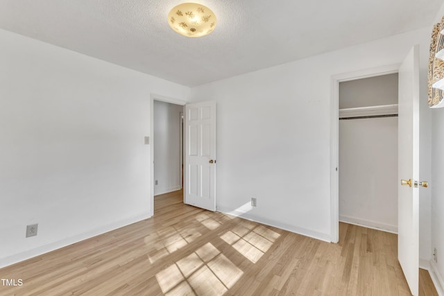 unfurnished bedroom with a closet, light hardwood / wood-style floors, and a textured ceiling