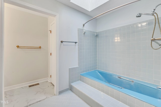 bathroom with tiled shower / bath and a skylight