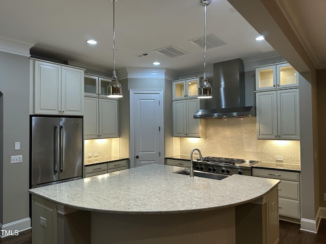 kitchen with stainless steel refrigerator, light stone countertops, a center island with sink, and wall chimney range hood