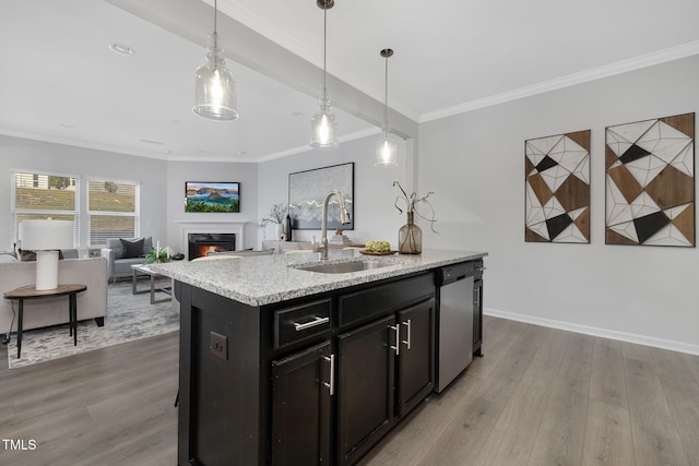 kitchen featuring sink, stainless steel dishwasher, wood-type flooring, decorative light fixtures, and a center island with sink