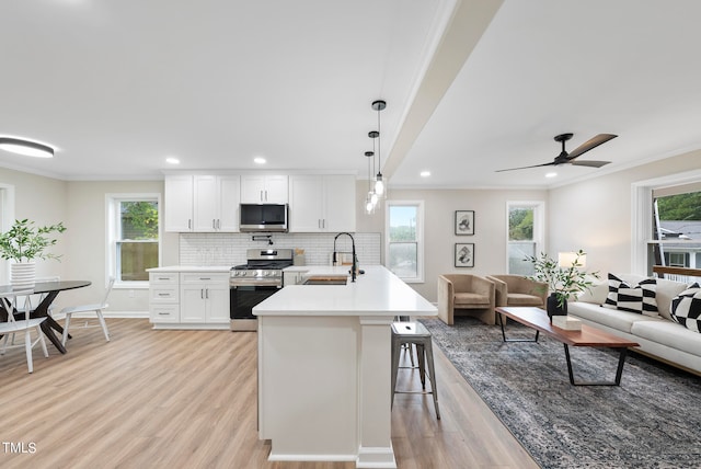 kitchen featuring pendant lighting, white cabinets, stainless steel appliances, and plenty of natural light