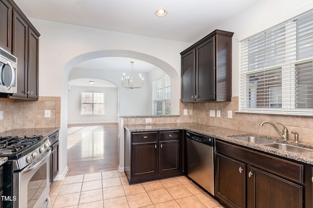 kitchen with dark brown cabinetry, sink, stainless steel appliances, backsplash, and pendant lighting