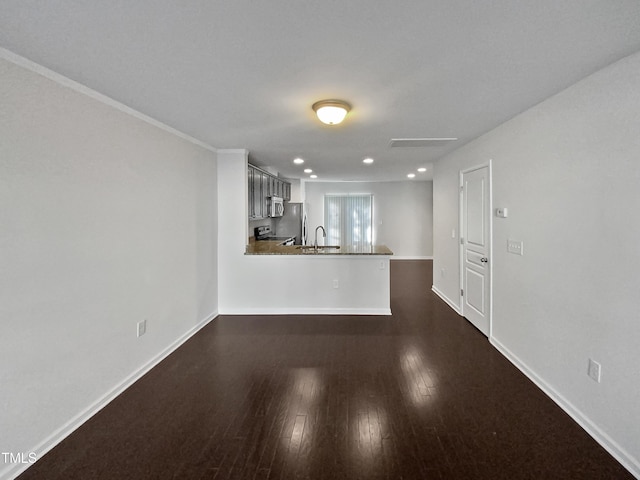 unfurnished living room with crown molding, dark wood-type flooring, and sink