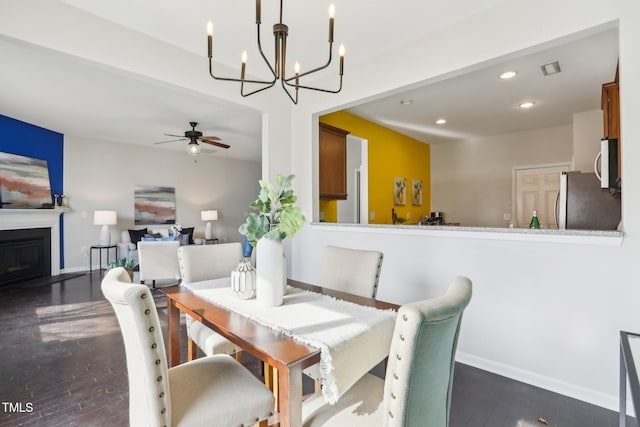 dining area featuring dark hardwood / wood-style flooring and ceiling fan with notable chandelier