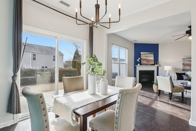 dining area with ceiling fan with notable chandelier and hardwood / wood-style floors