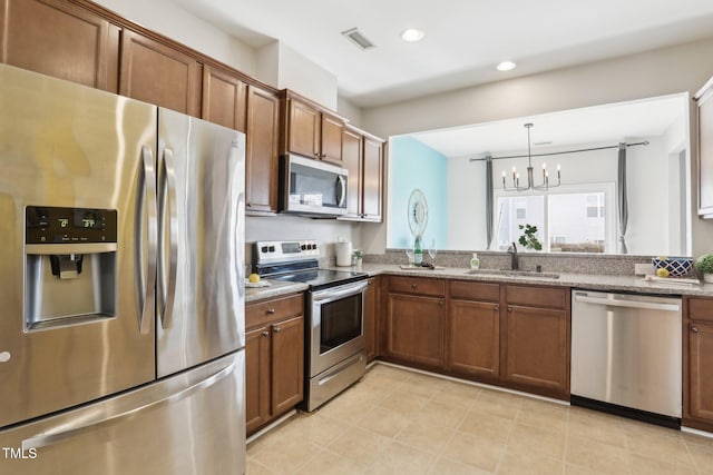 kitchen with sink, an inviting chandelier, hanging light fixtures, stainless steel appliances, and light stone countertops