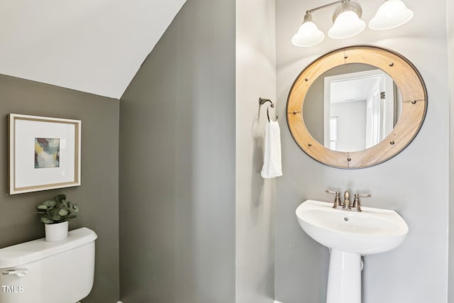 bathroom featuring sink, toilet, and vaulted ceiling