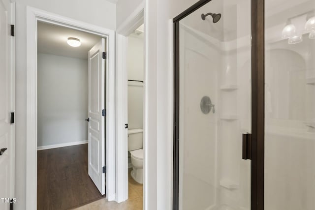 bathroom featuring hardwood / wood-style floors, toilet, and walk in shower