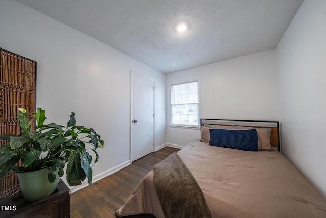 bedroom with a textured ceiling and dark hardwood / wood-style floors