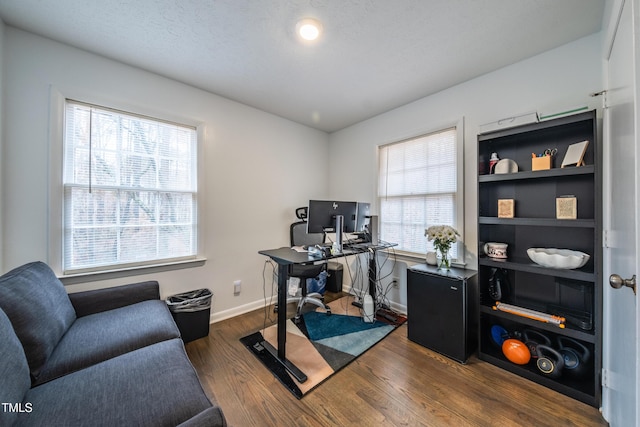 office featuring dark wood-type flooring, a healthy amount of sunlight, and a textured ceiling