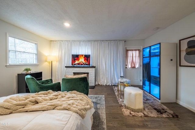 bedroom with access to outside, dark hardwood / wood-style floors, and a stone fireplace