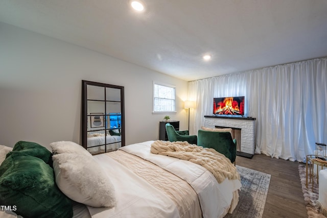 bedroom with dark hardwood / wood-style floors and a fireplace