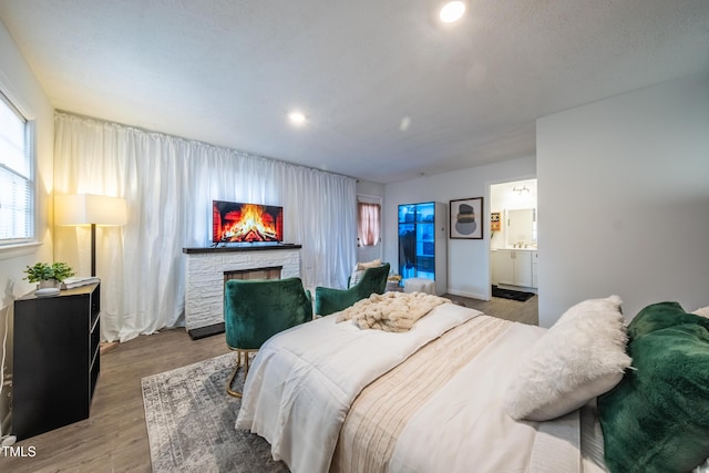 bedroom featuring ensuite bath, a fireplace, and light hardwood / wood-style floors