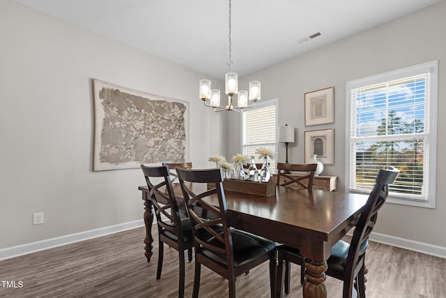 dining room with wood-type flooring and an inviting chandelier