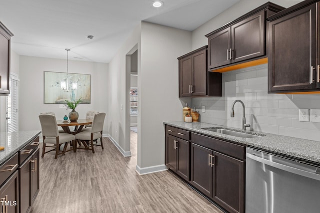 kitchen featuring dishwasher, light wood-type flooring, light stone countertops, and sink