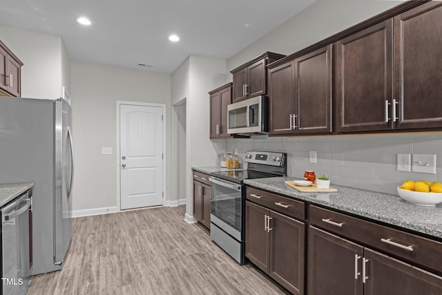 kitchen with light hardwood / wood-style flooring, light stone countertops, tasteful backsplash, dark brown cabinets, and stainless steel appliances