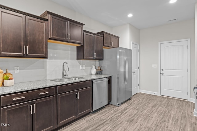 kitchen featuring stainless steel appliances, light hardwood / wood-style flooring, tasteful backsplash, and sink