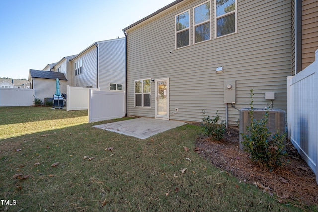 rear view of property featuring a yard, central AC unit, and a patio area