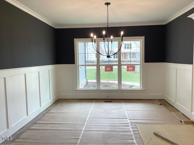 unfurnished dining area with a notable chandelier, plenty of natural light, and crown molding