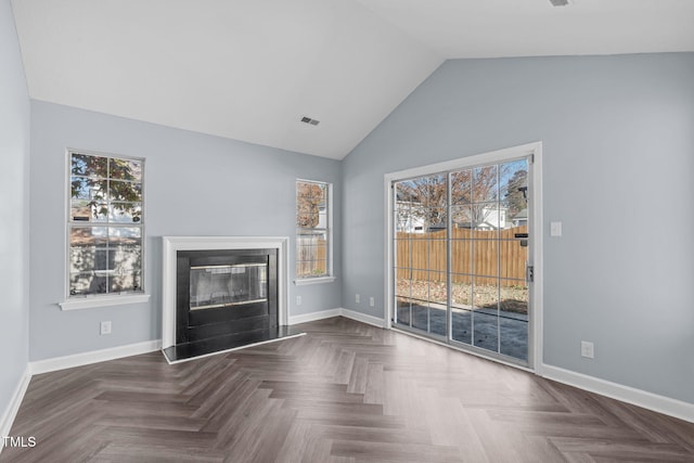 unfurnished living room featuring plenty of natural light, dark parquet floors, and lofted ceiling